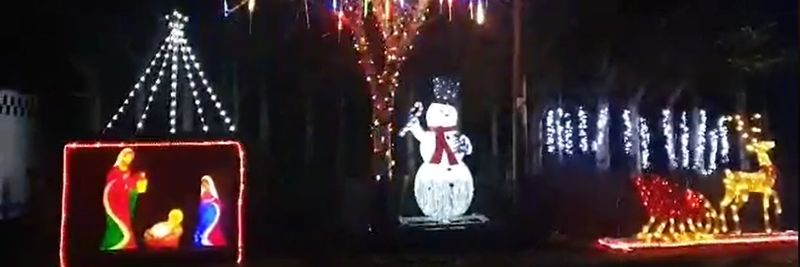 a dark background with a snoman, nativity and reigndeer light display